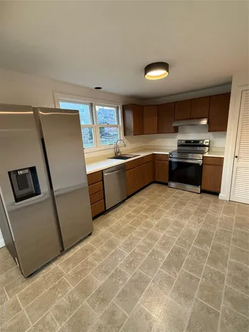 a large kitchen with granite countertop a refrigerator and a stove top oven