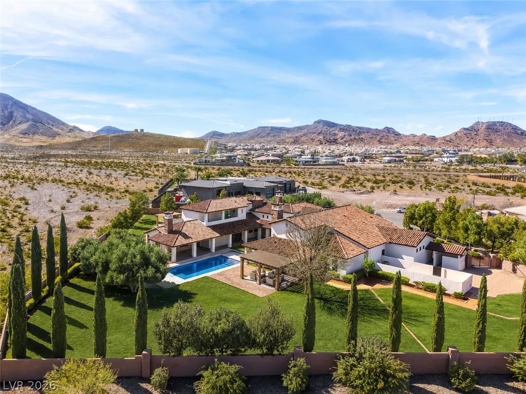 1140 Julie Road Henderson, NV 89002 - Photo 17 of 38 An aerial perspective reveals a luxurious desert oasis, showcasing a grand residence, manicured lawn, and inviting pool & spa.