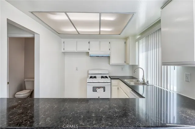 a kitchen with granite countertop white cabinets and white appliances