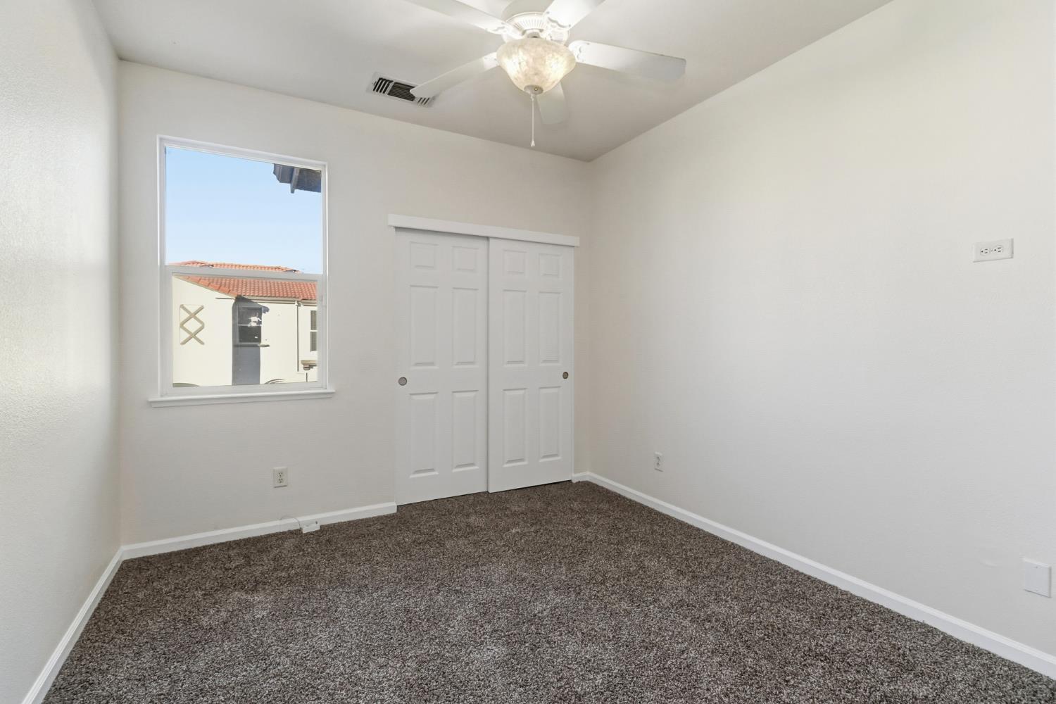 11832 Stoney Ridge Way Rancho Cordova, CA 95742 - Photo 31 of 44 an empty room with a chandelier fan and windows
