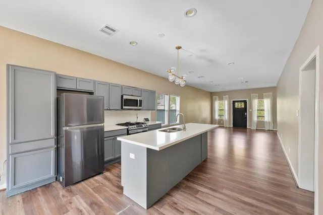 a large kitchen with stainless steel appliances granite countertop a lot of counter space and wooden floor