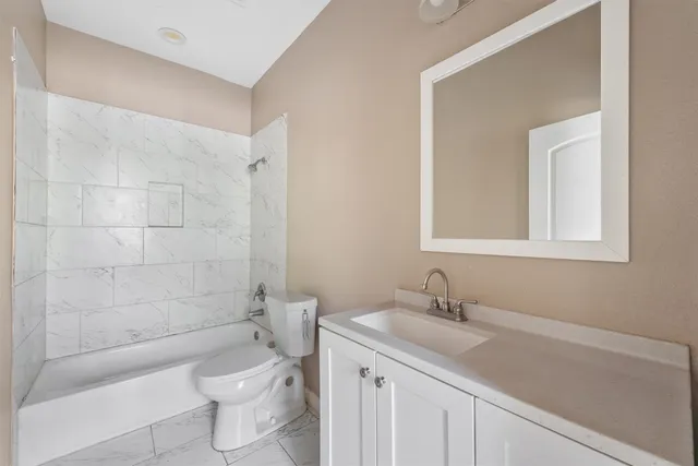 a bathroom with a granite countertop sink a toilet and shower