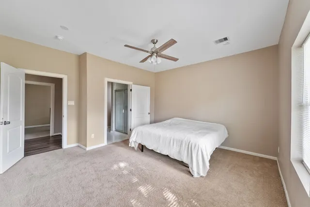 a spacious bedroom with a bed and a ceiling fan