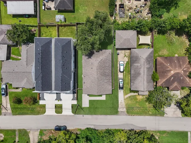 an aerial view of multiple houses with a yard and trees