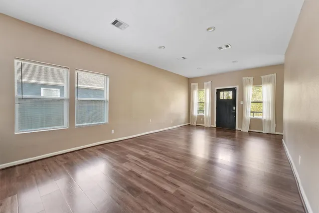 a view of an empty room with glass door and wooden floor