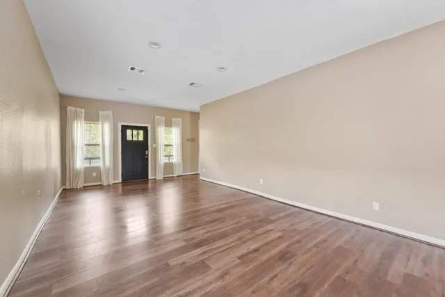 a view of an empty room with window and wooden floor