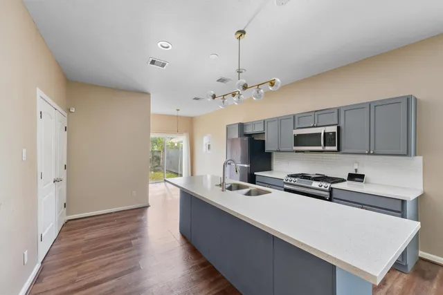 a room with stainless steel appliances kitchen island a sink a stove and cabinets