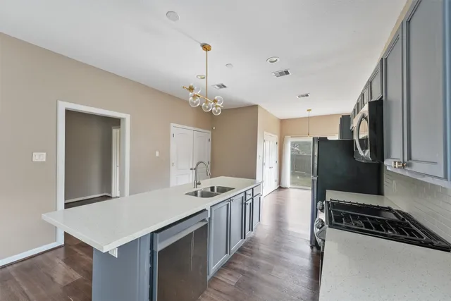 a kitchen with stainless steel appliances a stove a sink dishwasher a refrigerator white cabinets and wooden floor