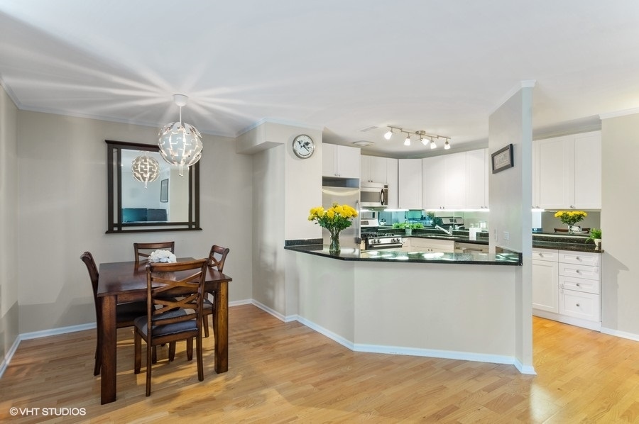 6102 North Sheridan Road, Unit 410 Chicago, IL 60660 - Photo 11 of 12 a kitchen with stainless steel appliances kitchen island granite countertop a table and chairs in it