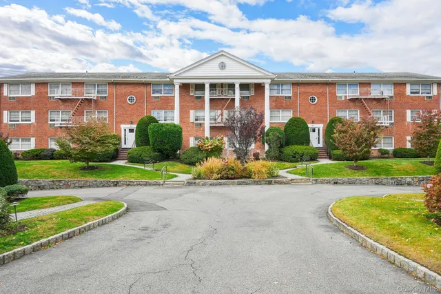 a view of a brick house with a yard and plants