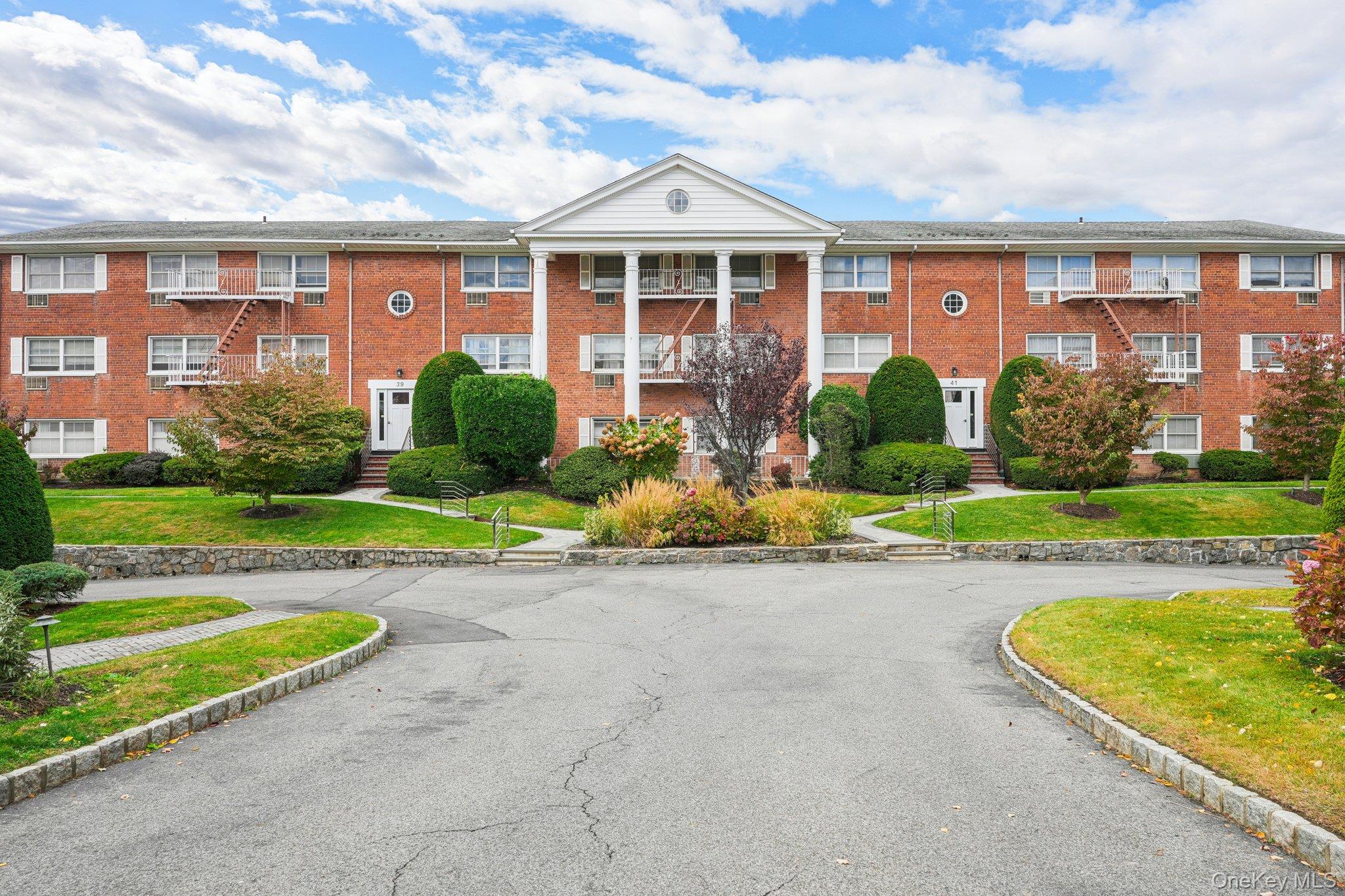 a view of a brick house with a yard and plants