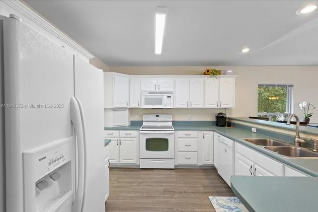 a kitchen with stainless steel appliances granite countertop a white cabinets and a refrigerator