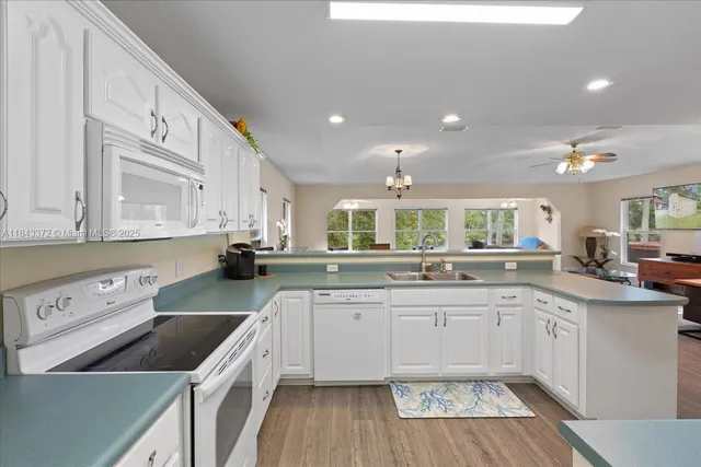 a kitchen with a sink dishwasher a stove and white cabinets with wooden floor