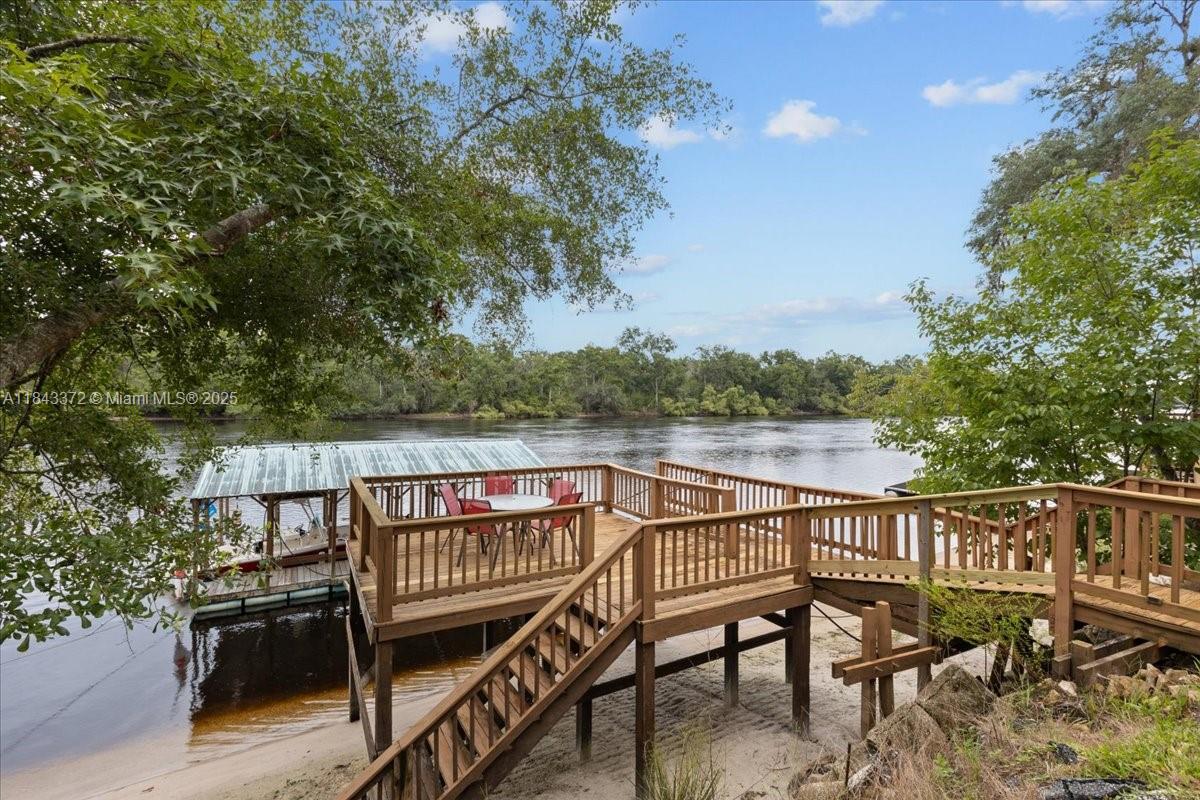 2159 Northwest 82nd Terrace Bell, FL 32619 - Photo 4 of 48 a view of a roof deck with table and chairs a barbeque with wooden floor and fence