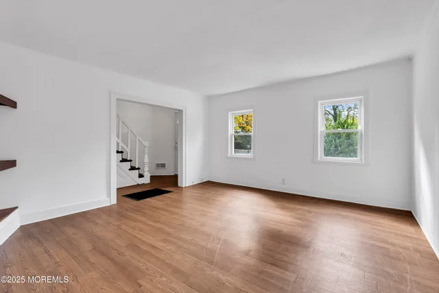 a view of an empty room with a window and wooden floor