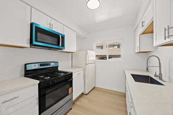 a kitchen with stainless steel appliances a stove microwave and sink