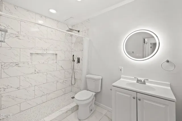 a bathroom with a toilet a sink a mirror and shower