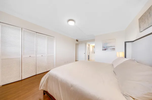 a spacious bedroom with a bed and wooden floor