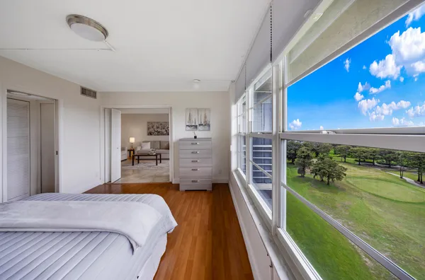 a bedroom with a bed table flowerpot and a kitchen view