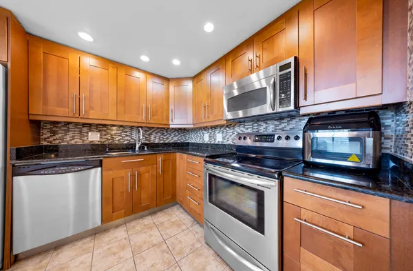 a kitchen with stainless steel appliances granite countertop a stove a sink and a microwave