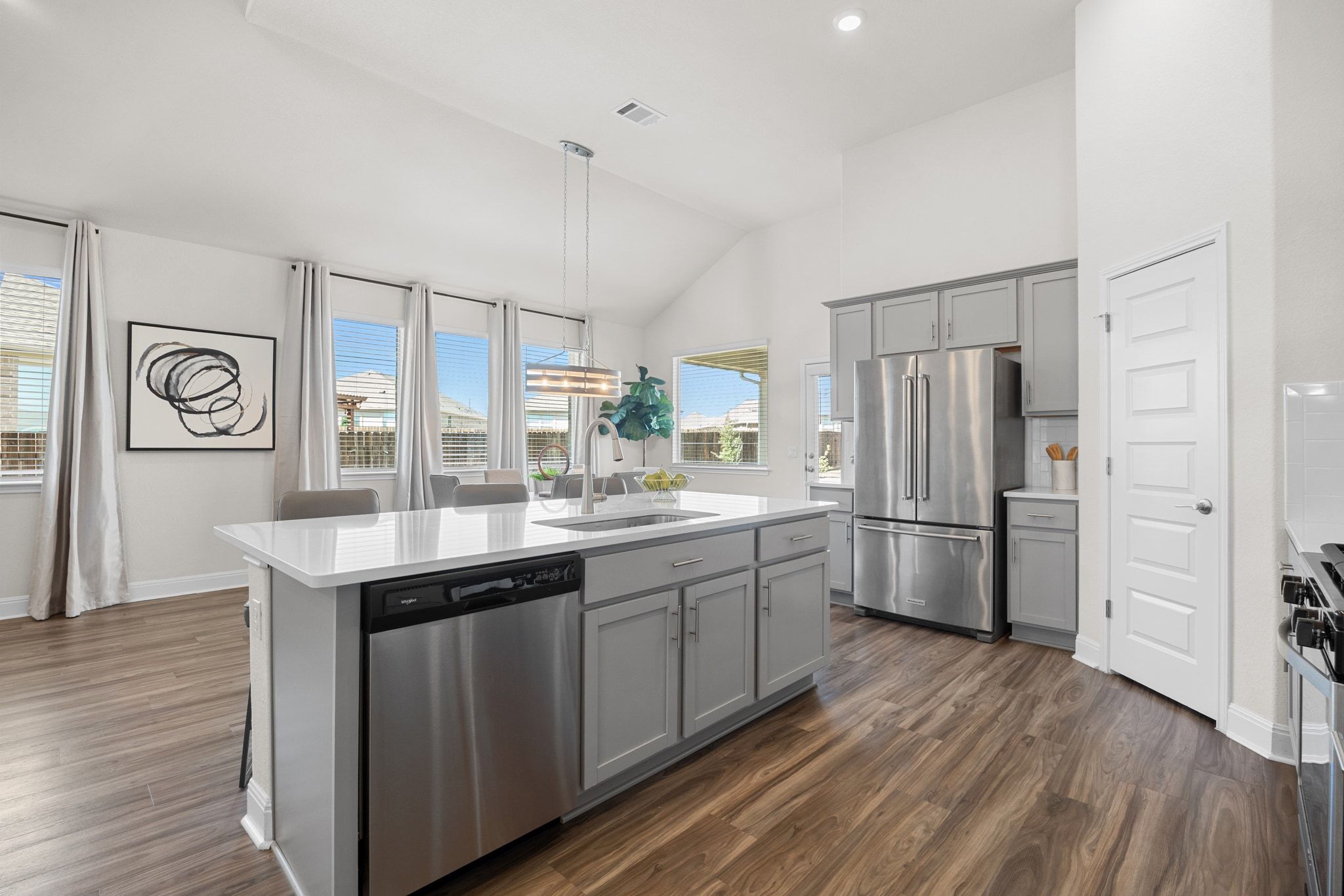16804 Guido Cove Pflugerville, TX 78660 - Photo 9 of 38 Kitchen with gray cabinets, stainless steel appliances, decorative light fixtures, a kitchen island with sink, and dark wood-style floors