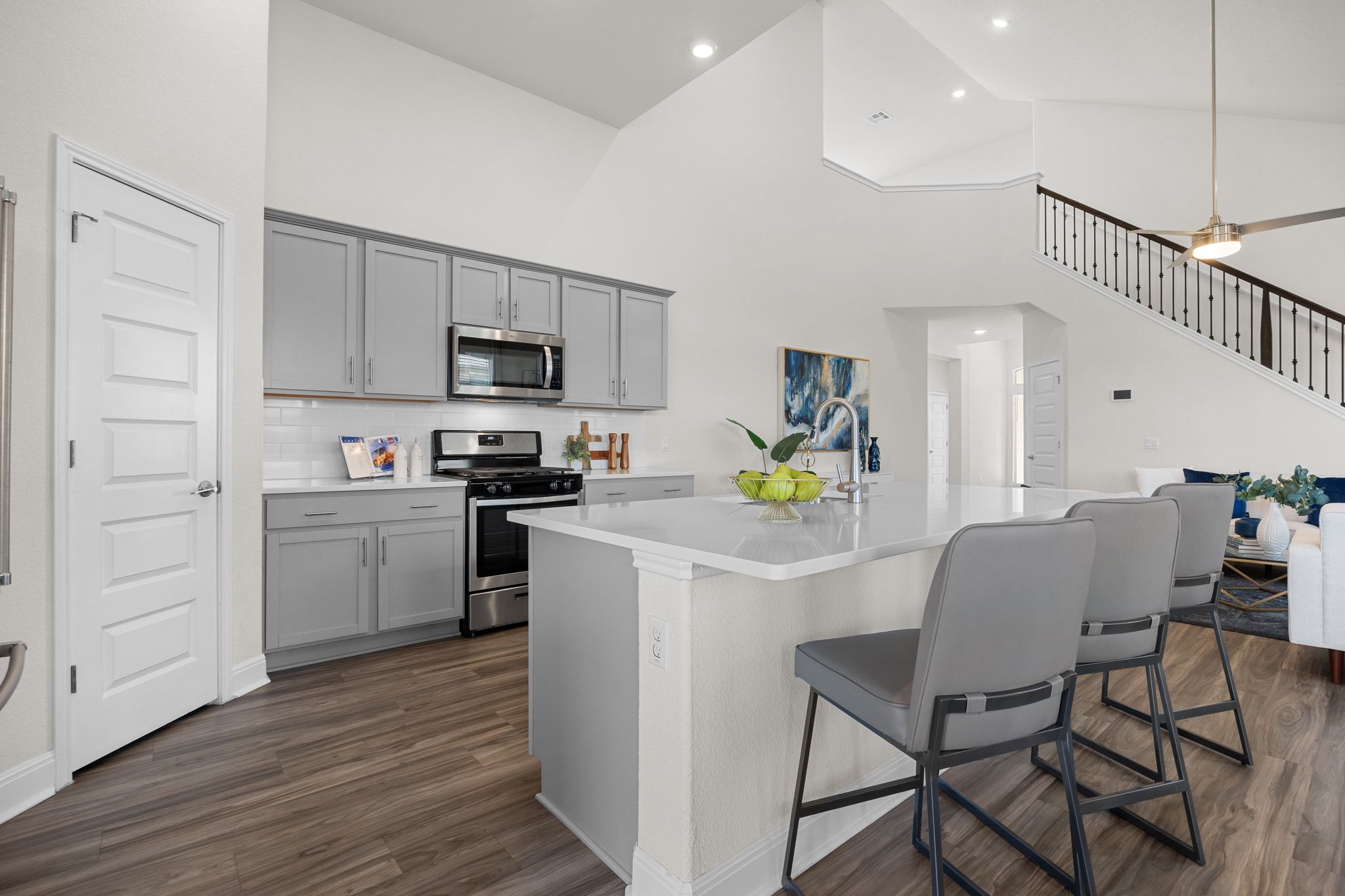 16804 Guido Cove Pflugerville, TX 78660 - Photo 10 of 38 Kitchen featuring stainless steel appliances, gray cabinetry, a kitchen breakfast bar, a kitchen island with sink, and high vaulted ceiling