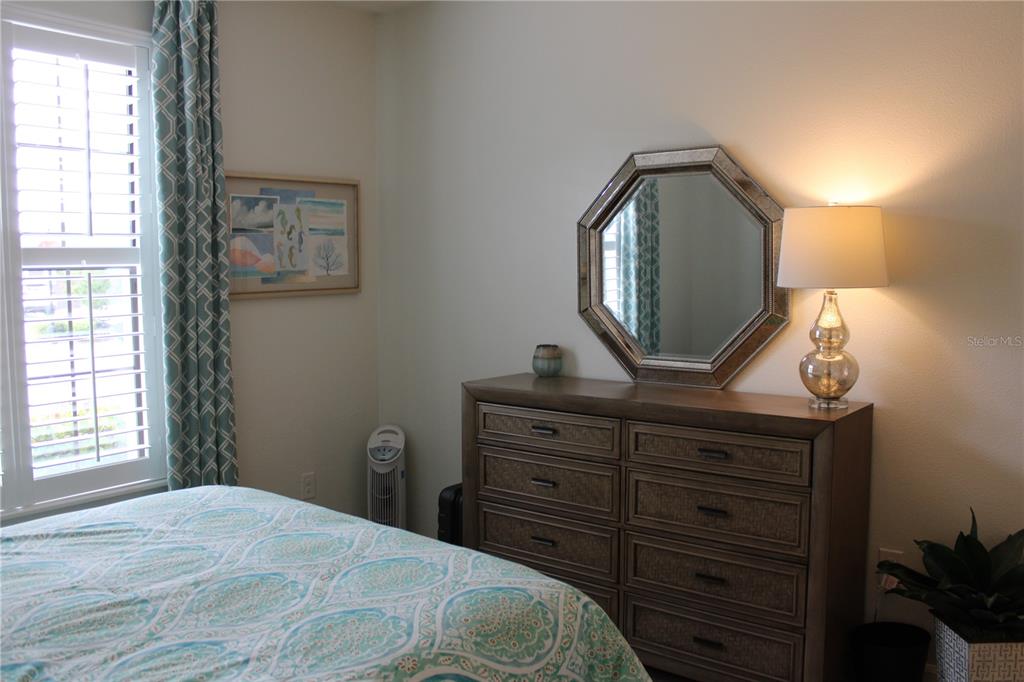 13711 Messina Loop, Unit 104 Bradenton, FL 34211 - Photo 25 of 70 a bedroom with a bed and a mirror on dresser