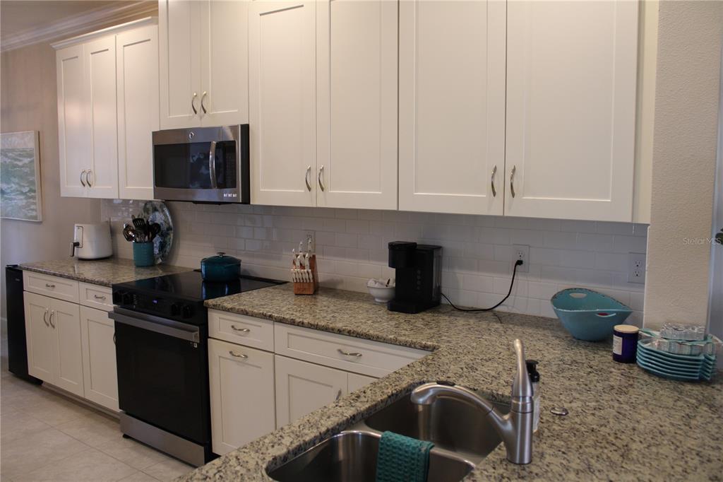 13711 Messina Loop, Unit 104 Bradenton, FL 34211 - Photo 4 of 70 a kitchen with granite countertop a sink dishwasher stove and cabinets
