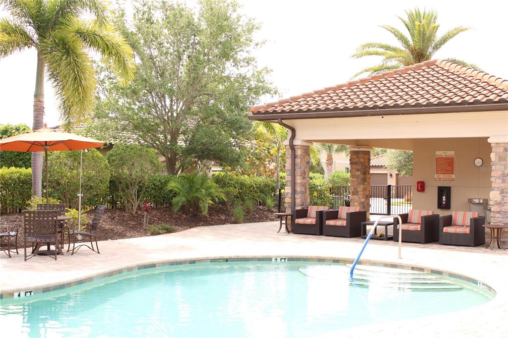 13711 Messina Loop, Unit 104 Bradenton, FL 34211 - Photo 51 of 70 a view of patio with table and chairs under an umbrella with large trees