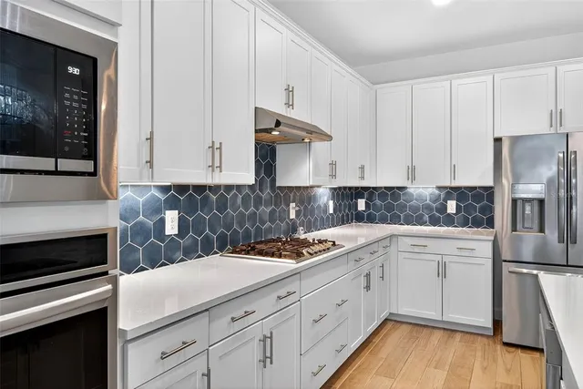 an empty room with wooden floor ceiling fan and windows