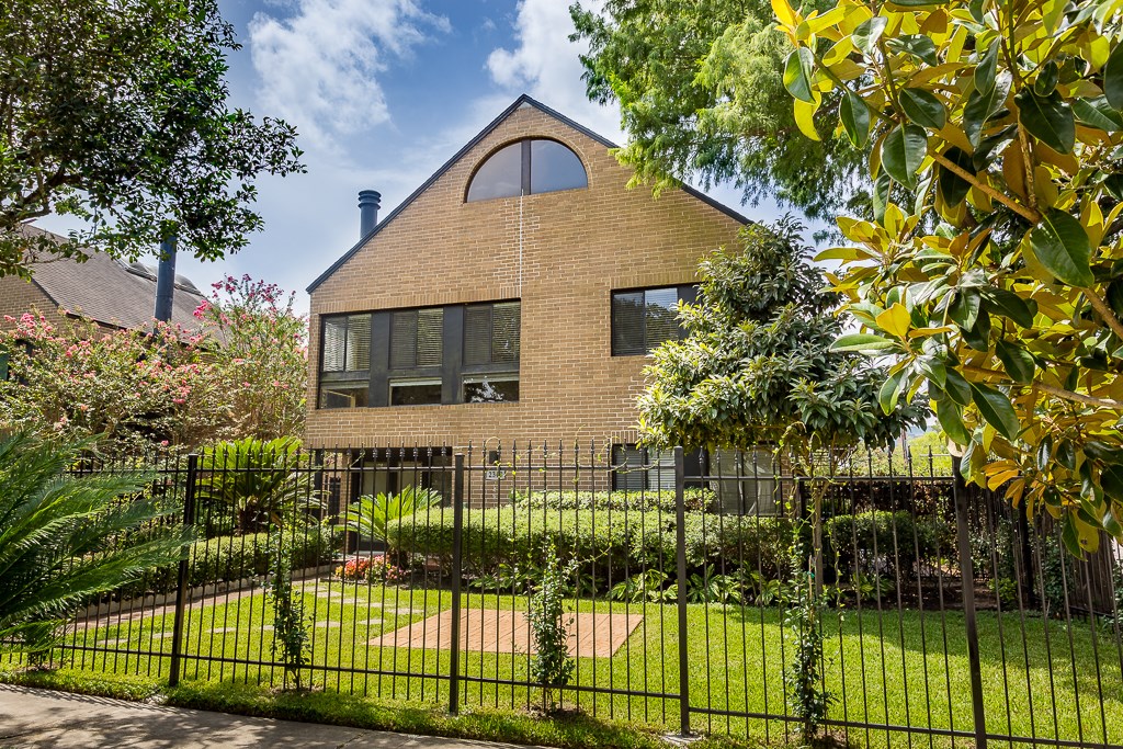 2349 Albans Road, Unit 2 Houston, TX 77005 - Photo 2 of 25 Inviting brick home features a unique arched window design and a spacious, well-maintained yard with lush greenery, enclosed by wrought iron fence. Perfect for those seeking charm and privacy.