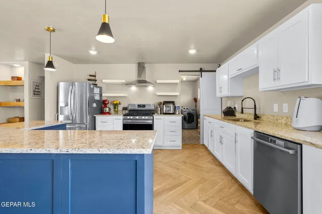a kitchen with stainless steel appliances granite countertop a sink a stove and a wooden floors