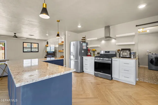 a large kitchen with granite countertop a large counter top stainless steel appliances and cabinets