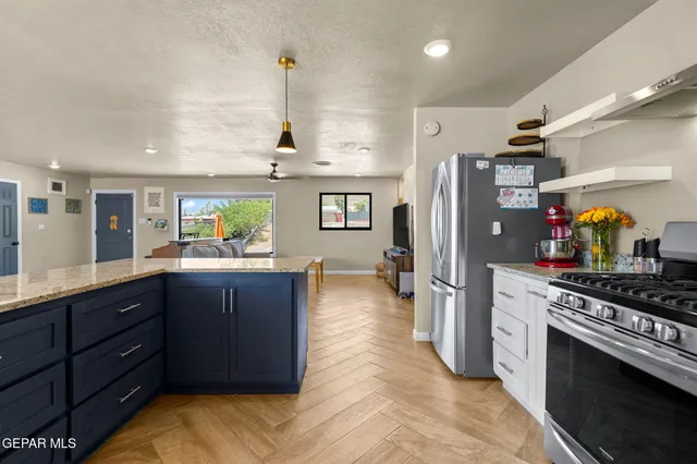 a kitchen with stainless steel appliances granite countertop a refrigerator a stove and a wooden floors