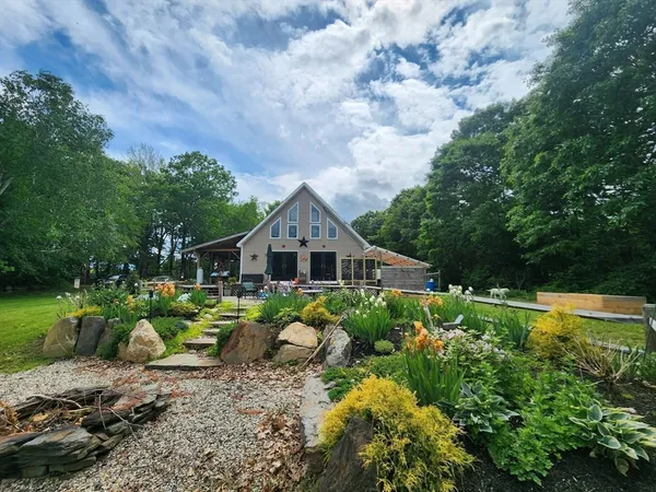 a view of a house with a big yard plants and large trees