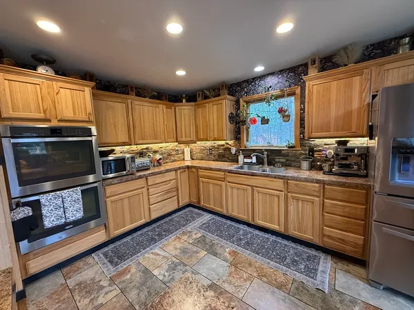 a kitchen with stainless steel appliances granite countertop a refrigerator a stove top oven a sink and dishwasher
