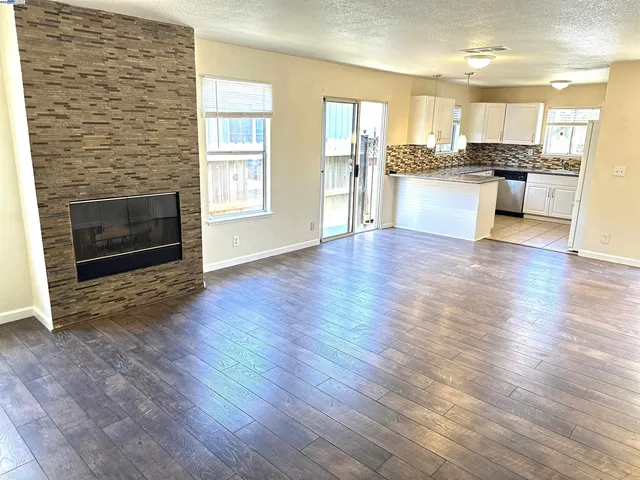 a open kitchen with granite countertop a stove top oven a sink and a wooden floor