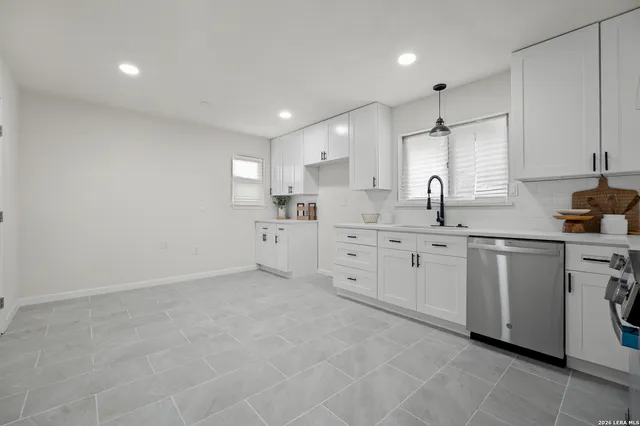 a kitchen with white cabinets sink and window