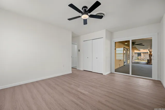an empty room with wooden floor and a ceiling fan