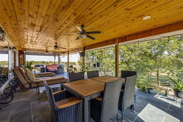 a view of a patio with table and chairs and couches with wooden floor and fence