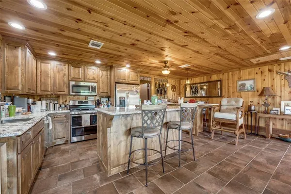 a kitchen with lots of wooden cabinets appliances and furniture