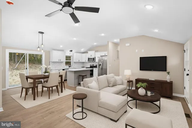 a living room with furniture kitchen view and a flat screen tv