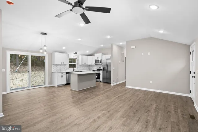 a view of kitchen with kitchen island white cabinets and stainless steel appliances