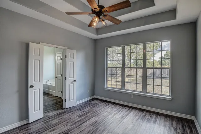 a view of an empty room with a window and wooden floor