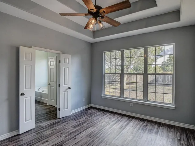 a view of an empty room with a window and wooden floor