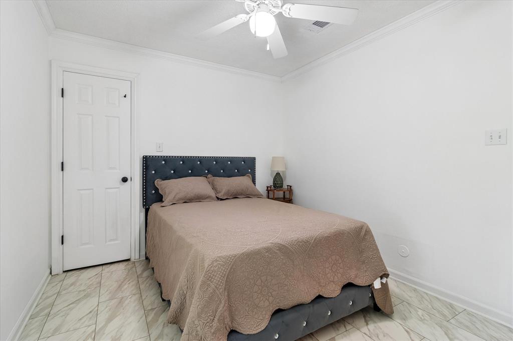3007 McReynolds Road Sanger, TX 76266 - Photo 13 of 39 Neutral white walls with crown molding, ceiling fan, and white paneled door with black hardware