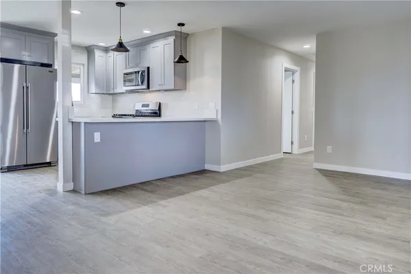 a large kitchen with stainless steel appliances granite countertop a refrigerator a sink a stove a microwave and wooden floors