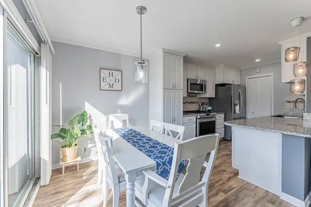 a kitchen with stainless steel appliances granite countertop a stove top oven a refrigerator a sink and a dining table with wooden floor