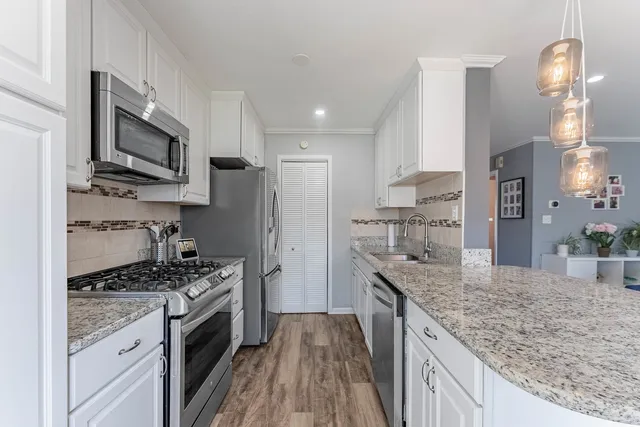 a kitchen with stainless steel appliances granite countertop a sink stove microwave and refrigerator