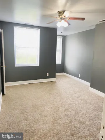 an empty room with windows and fan